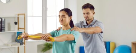Young woman doing muscle rehabilitation exercises with help of her physiotherapist